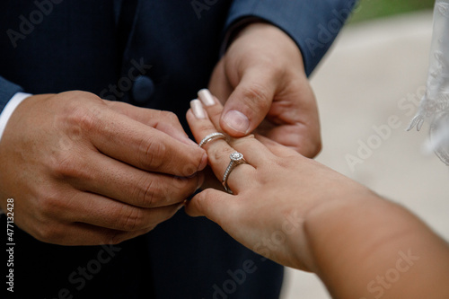Wedding engagement rings Married couple exchange wedding rings at a wedding ceremony Groom in black suit put a ring on the finger of his lovely wife Concept wedding details Happy family Close up 