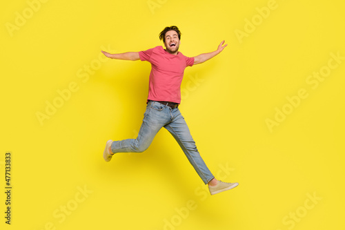 Full body photo of hooray brunet young guy run wear red t-shirt jeans shoes isolated on yellow background