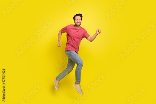 Full size photo of impressed beard young guy run wear red t-shirt jeans sneakers isolated on yellow background