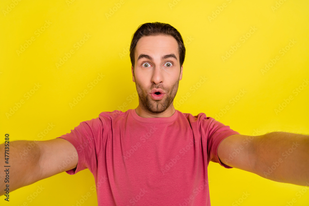 Photo of shocked influencer guy make selfie funny omg face wear pink t-shirt isolated yellow color background Photo of shocked influencer guy make selfie funny omg face wear pink t-shirt isolated yellow color background