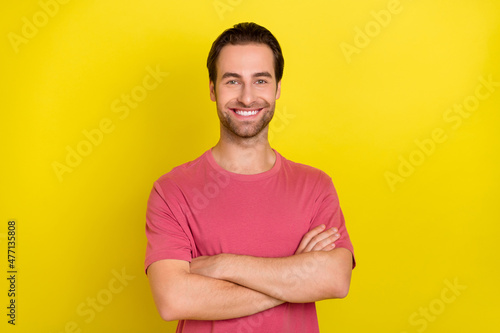 Photo of cheerful self-assured guy folded hands beaming smile wear pink t-shirt isolated yellow color background