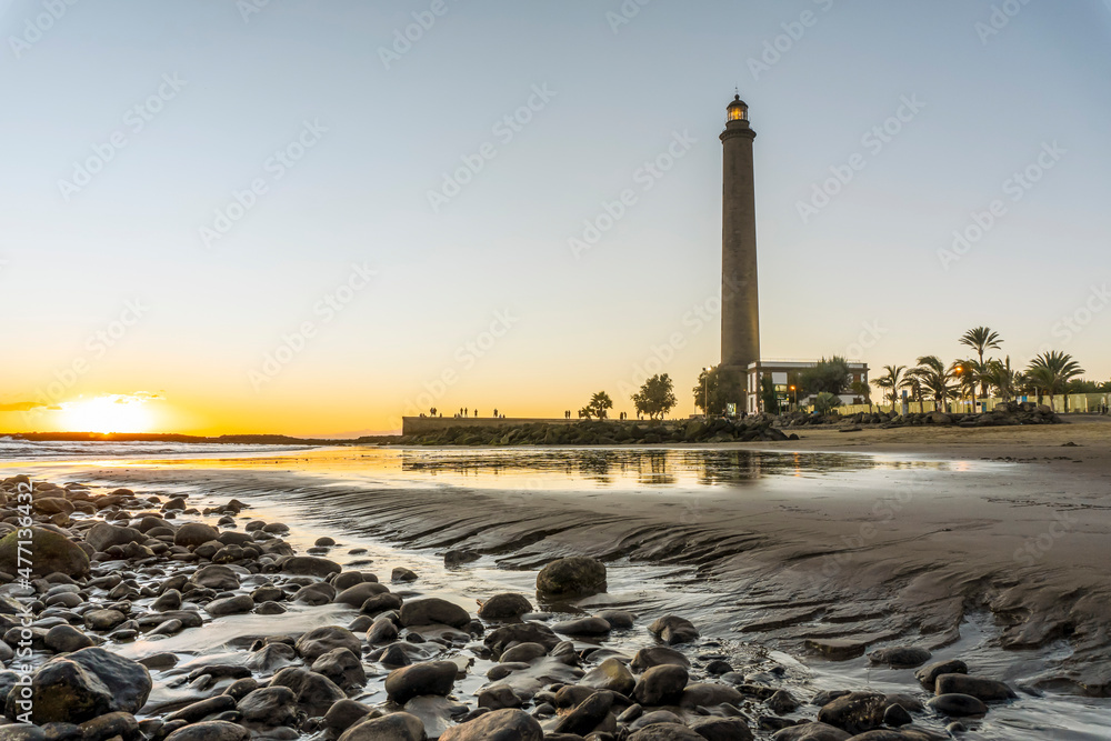 Obraz premium Lighthouse on rocky coast during sunset in Maspalomas, Gran Canaria, Spain