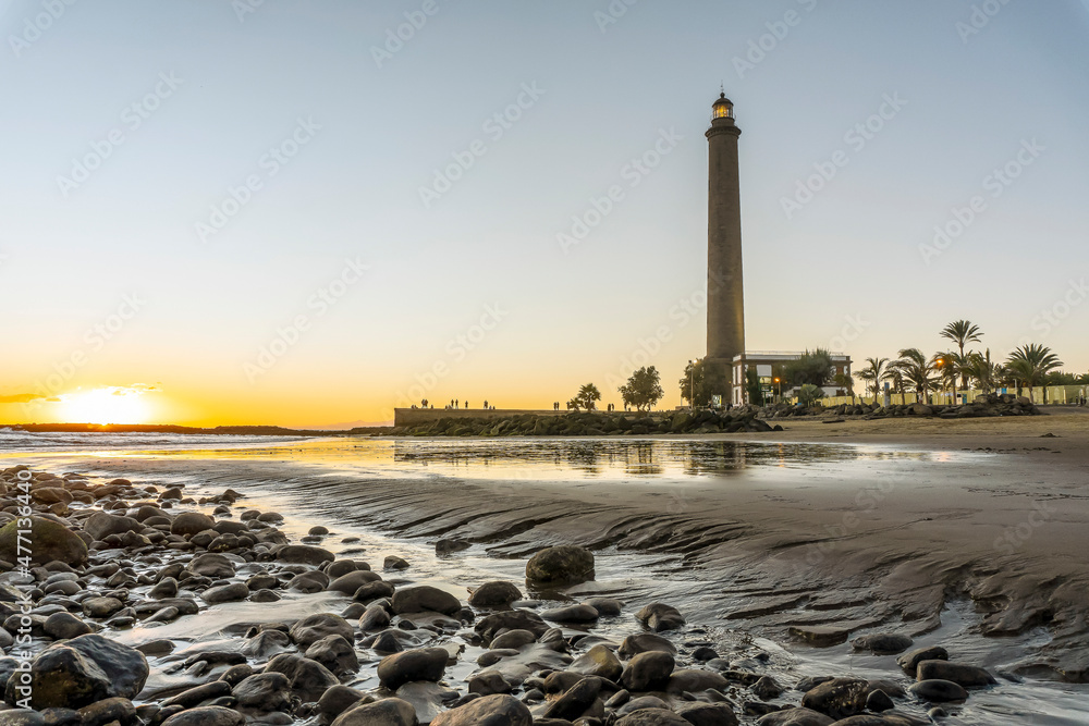 Fototapeta premium Lighthouse on rocky coast during sunset in Maspalomas, Gran Canaria, Spain