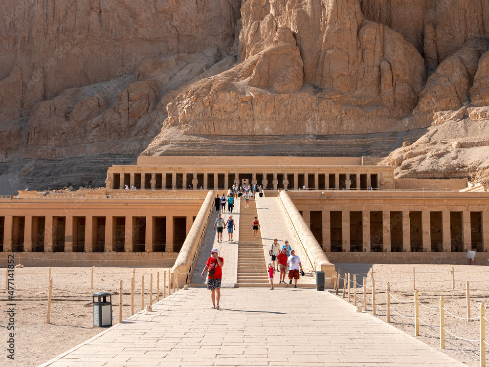 Luxor, Egypt - October 3, 2021: View of the main entrance to the temple of Queen Hatshepsut. People enter the temple on a stone staircase.. - obrazy, fototapety, plakaty 