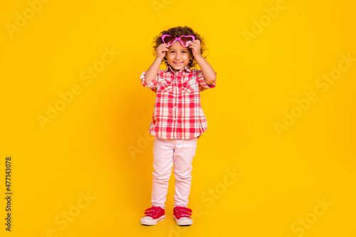 Photo of cute pretty school girl dressed checkered clothes arms heart spectacles smiling isolated yellow color background