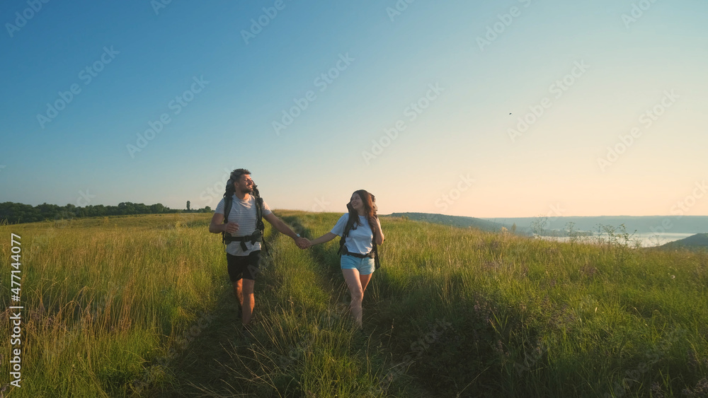 The two tourists walking with backpacks on a blue sky background The two tourists walking with backpacks on a blue sky background