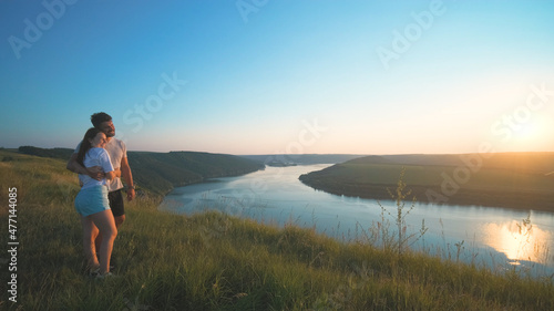 The romantic couple standing on a mountain top on a beautiful river background