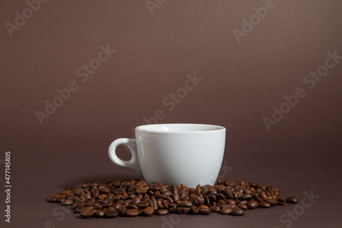 cup of coffee on a pile of coffee beans on a black background.