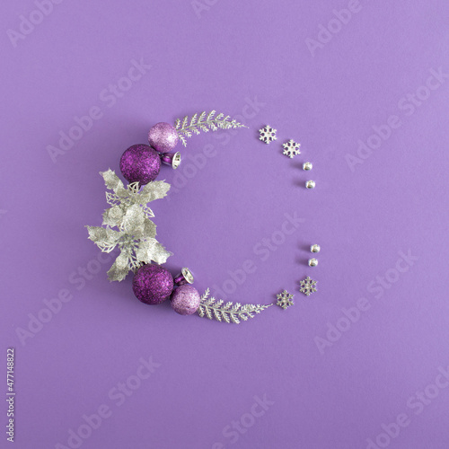 New year decoration layout with silver, pink and violet branches, baubles, bells, snowflake and flower. Xmas flat lay on purple background. Creative Christmas copy spices.