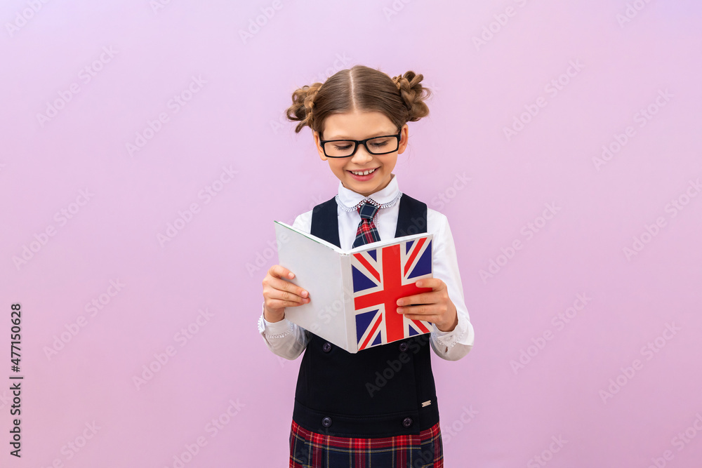 Fototapeta premium Learning English. a primary school student reads a textbook on an isolated background. education and study. copy space.