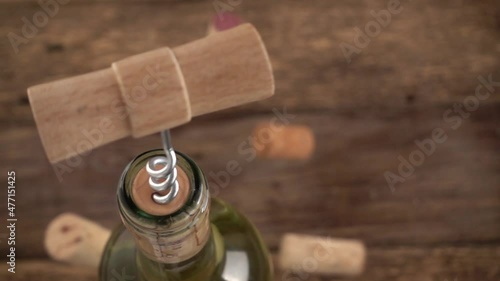 Wine corks fall on an old wooden board against the background of a corkscrew stuck in a bottle of wine. Slow motion. photo