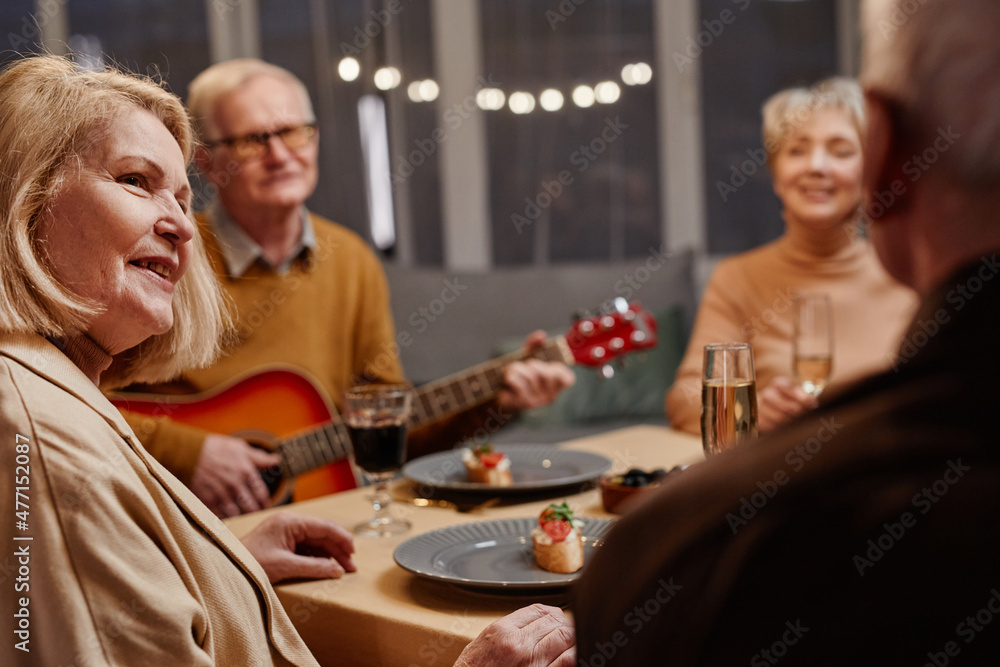 Over the shoulder view of old Caucasian woman tenderly looking at her husband sitting nearby while having dinner with friends Over the shoulder view of old Caucasian woman tenderly looking at her husband sitting nearby while having dinner with friends
