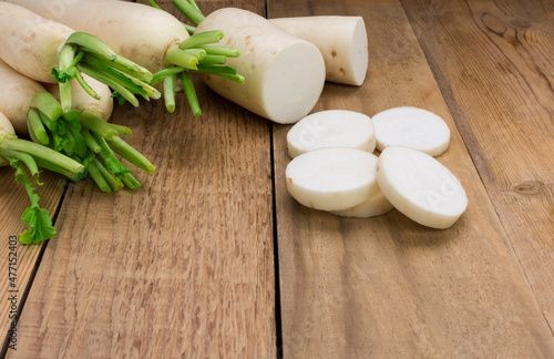 white radish and sliced ​​radishes, placed on a wooden table with a copy space