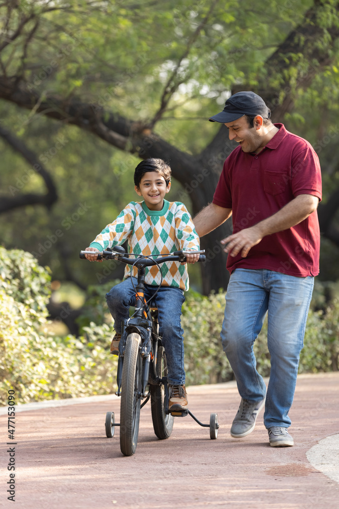 custom made wallpaper toronto digitalCheerful father teaching son riding bicycle while admiring view at park.