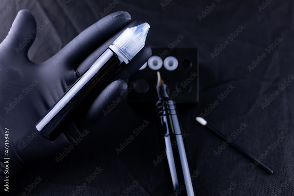 in the hands of a permanent eyebrow makeup artist there is a bottle with pigment and a tattoo machine in the hands of a permanent eyebrow makeup artist there is a bottle with pigment and a tattoo machine