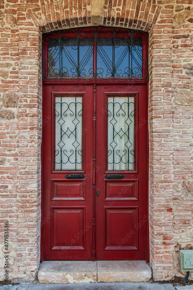 Close-up of the building's facade and an antique-style Wooden door. Textured stone tiles and an old wooden door