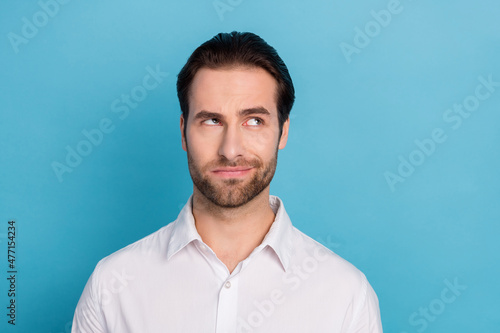 Photo of pensive intelligent doubtful guy look up empty space wear white shirt isolated blue color background © deagreez