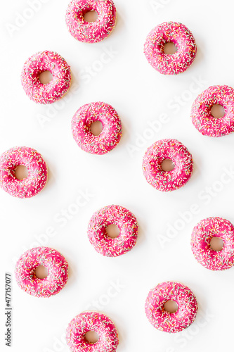 Pattern of pink glazed donutes with sprinkles, top view