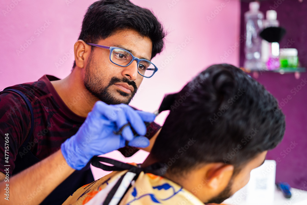 Fototapeta premium Close up shot of hairdresser busy in haircut at salon - concept of haircare, professional occupation and small business.