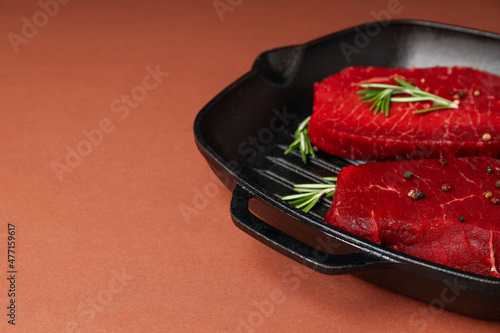 Concept of cooking with raw steak on brown background