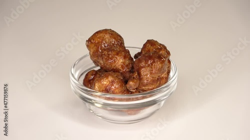 Loopable footage of many candied macadamia nuts spinning in a small bowl against white background. photo