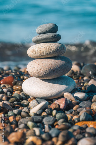 Beautiful pyramid of pebbles on the seashore on a sunny day  copy the space. Concept of balance  harmony. Vertical photo