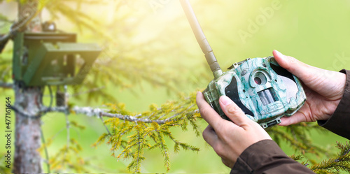 Photography Forester holding in hands camera trap or trail camera for automatic photography wild animals in to the deep forest with blur background