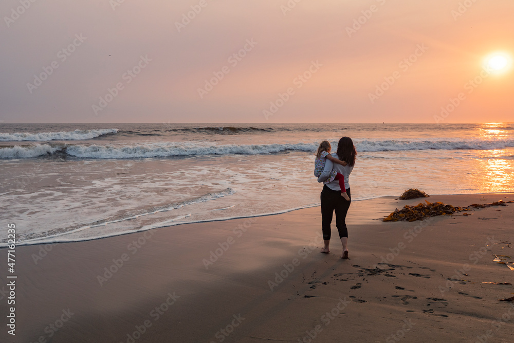 Mother and daughter (4-5) on beach at sunset Mother and daughter (4-5) on beach at sunset