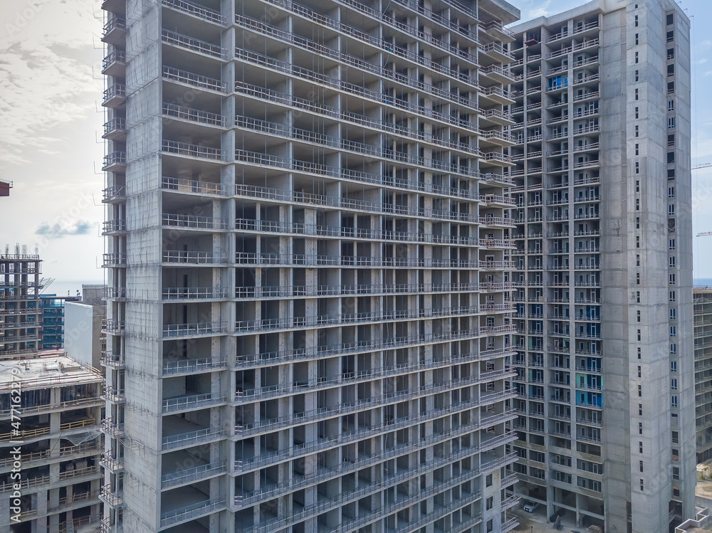 Drone view of the construction of multi-storey buildings on a summer day against the backdrop of sea