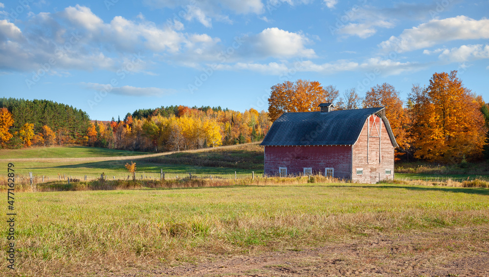 An old barn in a field with trees in autumn color on a bright afternoon in rural Michigan An old barn in a field with trees in autumn color on a bright afternoon in rural Michigan