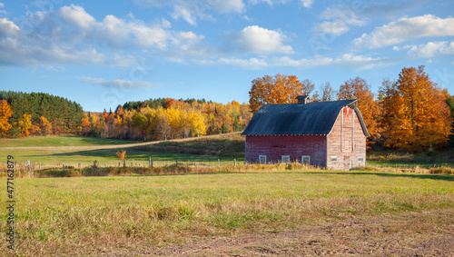 Foto An old barn in a field with trees in autumn color on a bright afternoon in rural