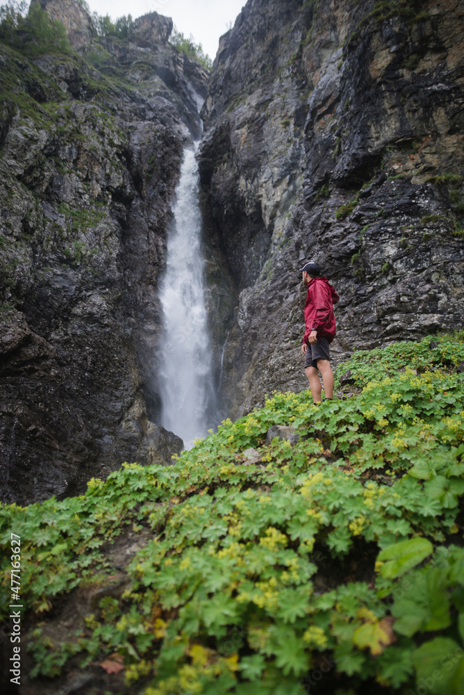 Russia , Karachay-Cherkessia, Arkhyz, Caucasus mountains, Hiker standing near waterfall Russia , Karachay-Cherkessia, Arkhyz, Caucasus mountains, Hiker standing near waterfall
