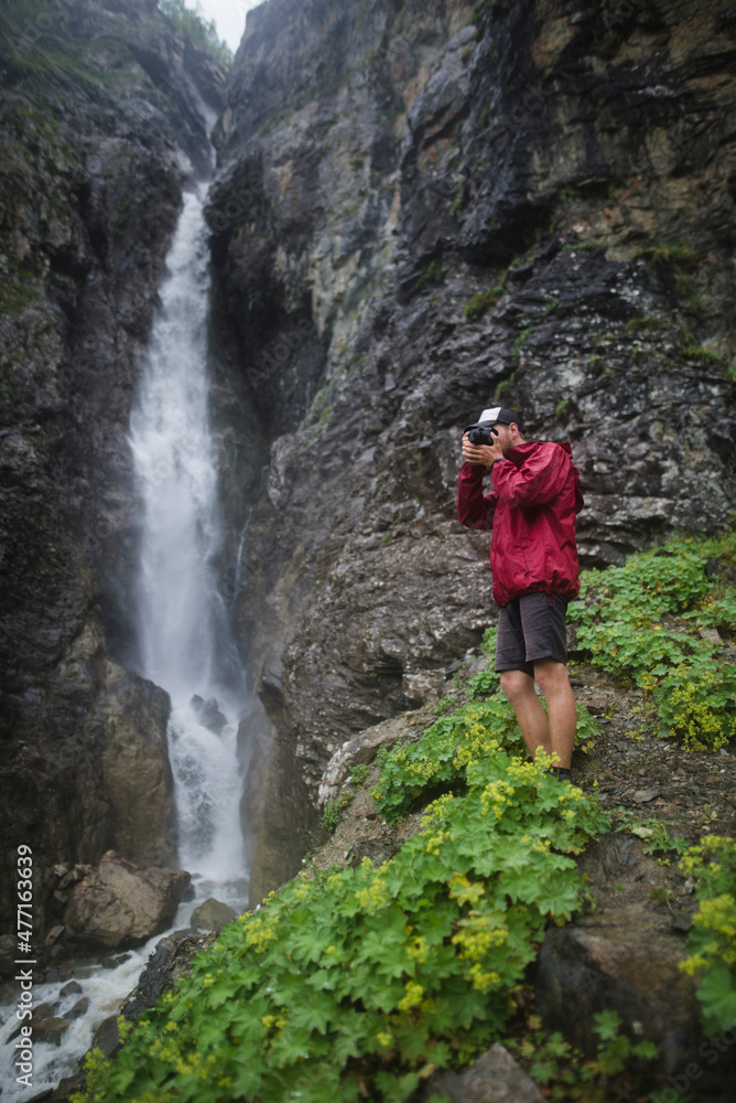Russia , Karachay-Cherkessia, Arkhyz, Caucasus mountains, Hiker taking picture near waterfall Russia , Karachay-Cherkessia, Arkhyz, Caucasus mountains, Hiker taking picture near waterfall