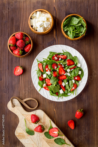 Top view of spinach salad with strawberry and goat cheese