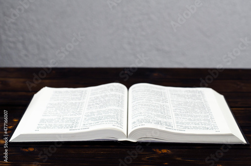 Open Bible, on a wooden table. Light from the book. Desktop.