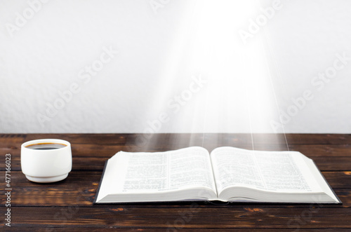 Open Bible on the table. A cup of coffee. Desktop. Workplace.