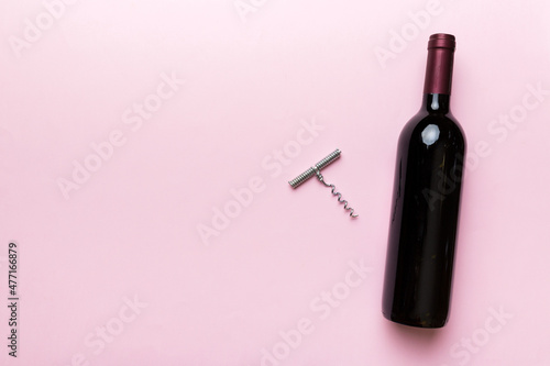 Fotografia One Bottle of red wine with corkscrew on colored table