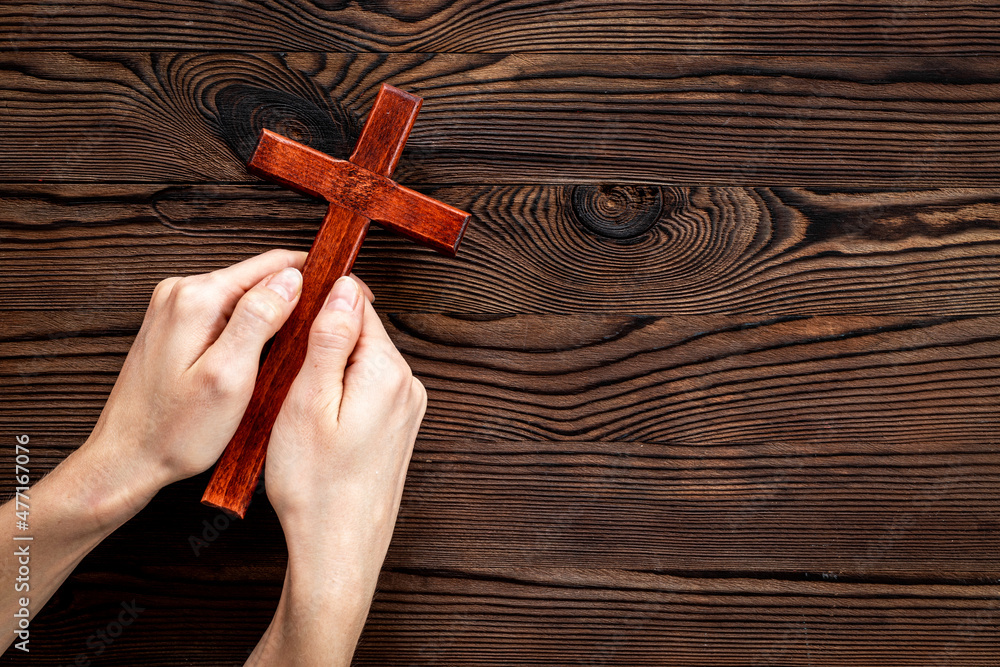 Christian wooden cross in hands. Faith and prayer concept