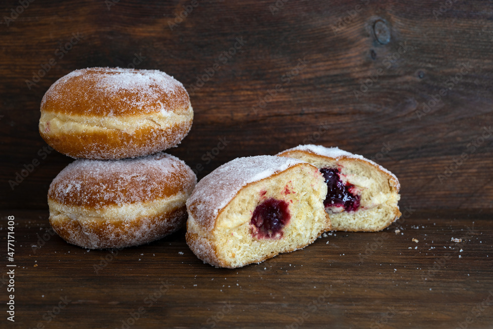 Berliner donuts or Krapfen filled with red jam, traditional sweet pastry for carnival and New Year, dark brown rustic wood, copy space, selected focus - obrazy, fototapety, plakaty 