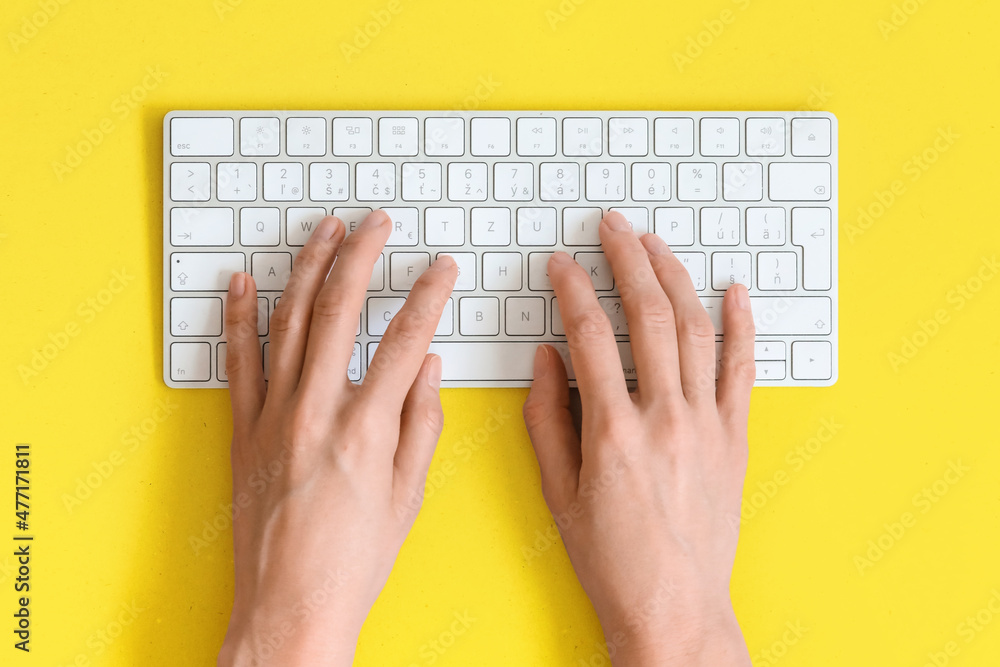 Top view on female elegant hands on a computer keyboard isolated yellow background and clipping. Assistance service respond on e mail. - obrazy, fototapety, plakaty 