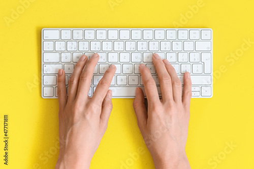 Top view on female elegant hands on a computer keyboard isolated yellow background and clipping. Assistance service respond on e mail.