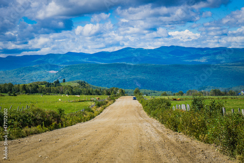 View of an unpaved road in the Charlevoix countryside with view on the mountains in the background