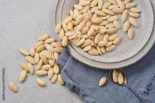 White peeled or blanched almonds. Healthy almond in a plate with napkin on gray granite background. Shallow depth of field