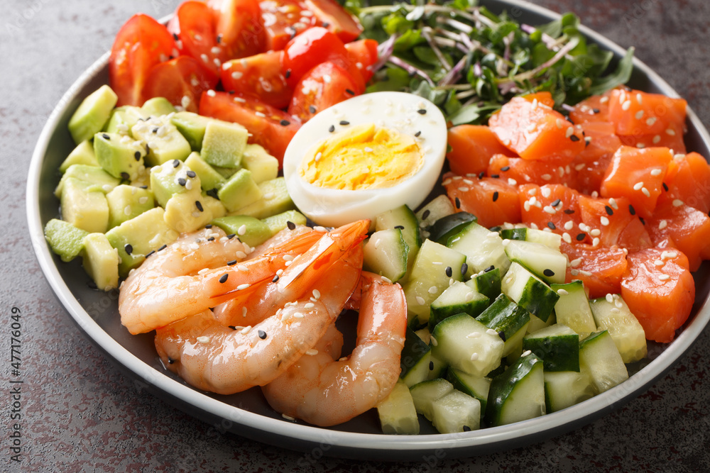 Organic breakfast of salmon, shrimps, eggs and fresh vegetables close-up in a plate on a concrete table. horizontal Organic breakfast of salmon, shrimps, eggs and fresh vegetables close-up in a plate on a concrete table. horizontal