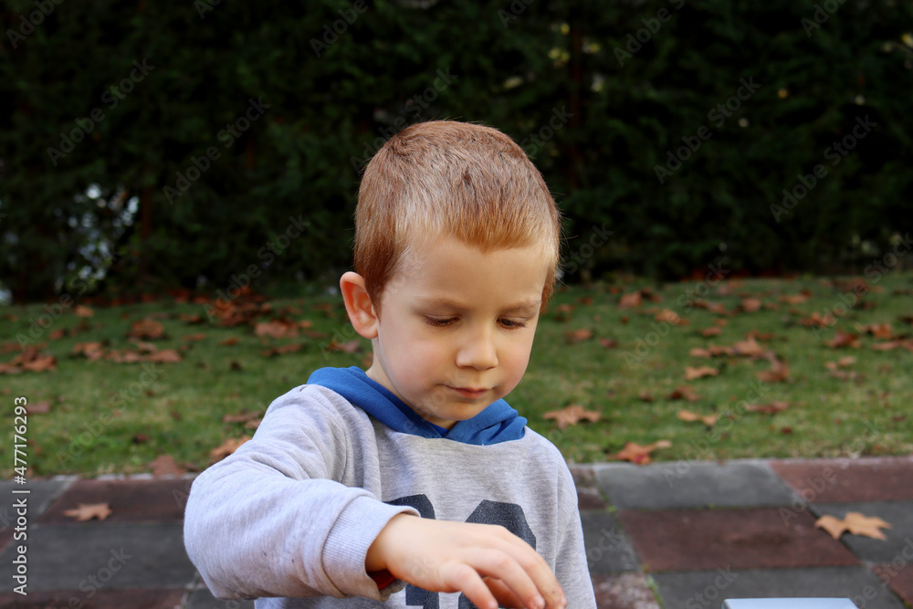 The blond boy looks at the toys with concentration. Four year old pensive boy The blond boy looks at the toys with concentration. Four year old pensive boy