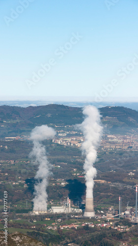 Chimeneas de vapor de fábrica en un valle cerca de una ciudad