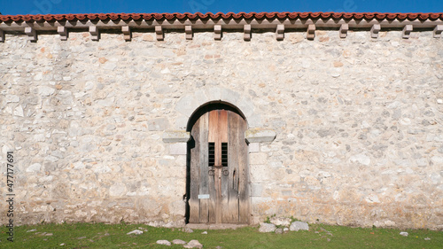 Puerta de madera con arco románico en construcción rústica de piedra en lo alto de una montaña