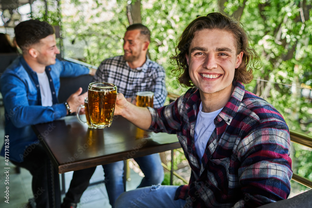 Portrait of a guy drinking beer in a pub, friends in the background. Portrait of a guy drinking beer in a pub, friends in the background.