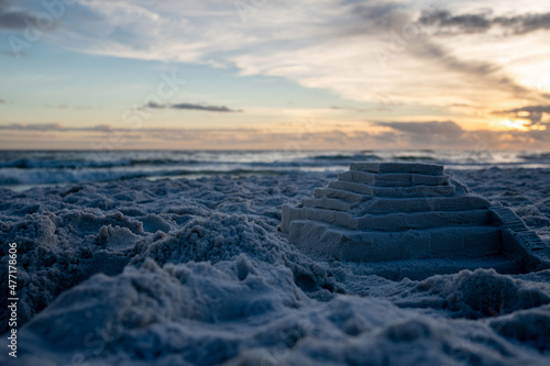 Sandcastle of temple with stairs on ocean beach during sunset