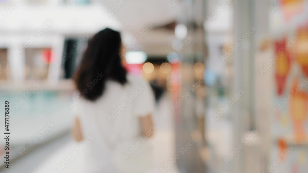Out of focus blurred background back view young curly brunette girl walking indoors in public place supermarket shopping center weekend moving woman shopper consumer looking sale in clothing store Out of focus blurred background back view young curly brunette girl walking indoors in public place supermarket shopping center weekend moving woman shopper consumer looking sale in clothing store